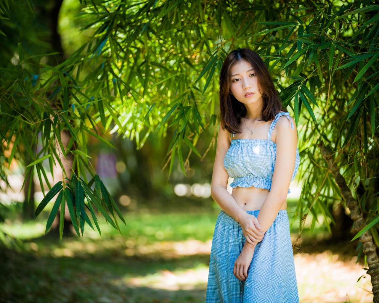 Молодая девушка в голубом костюме под деревом