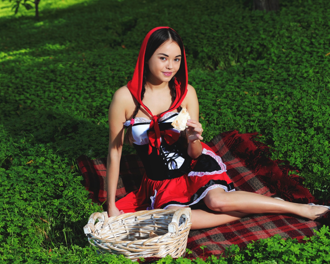 Молодая девушка в костюме сидит на траве, косплей