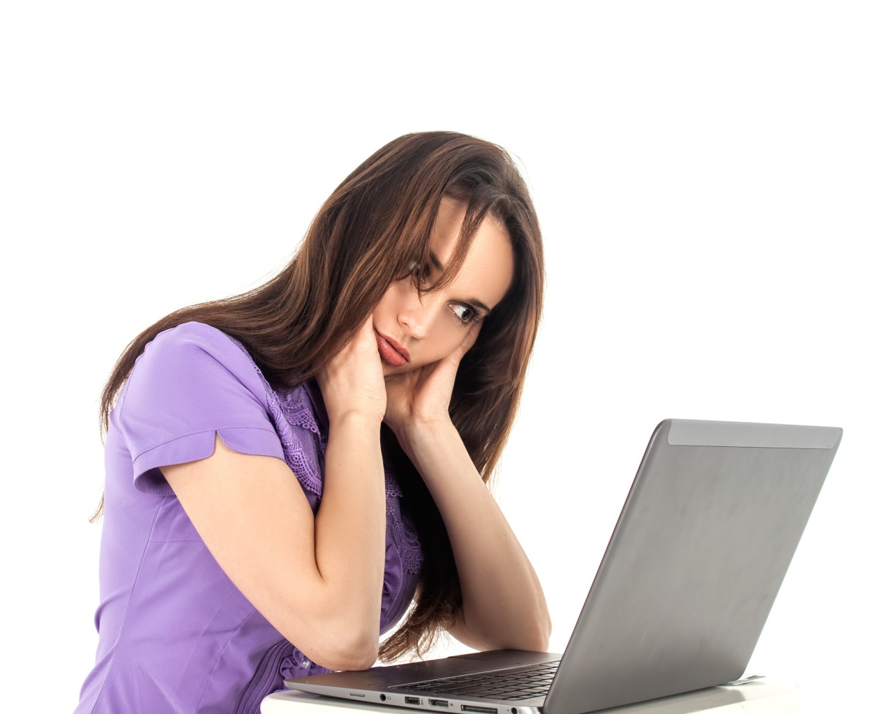 Молодая девушка сидит за ноутбуком на белом фоне