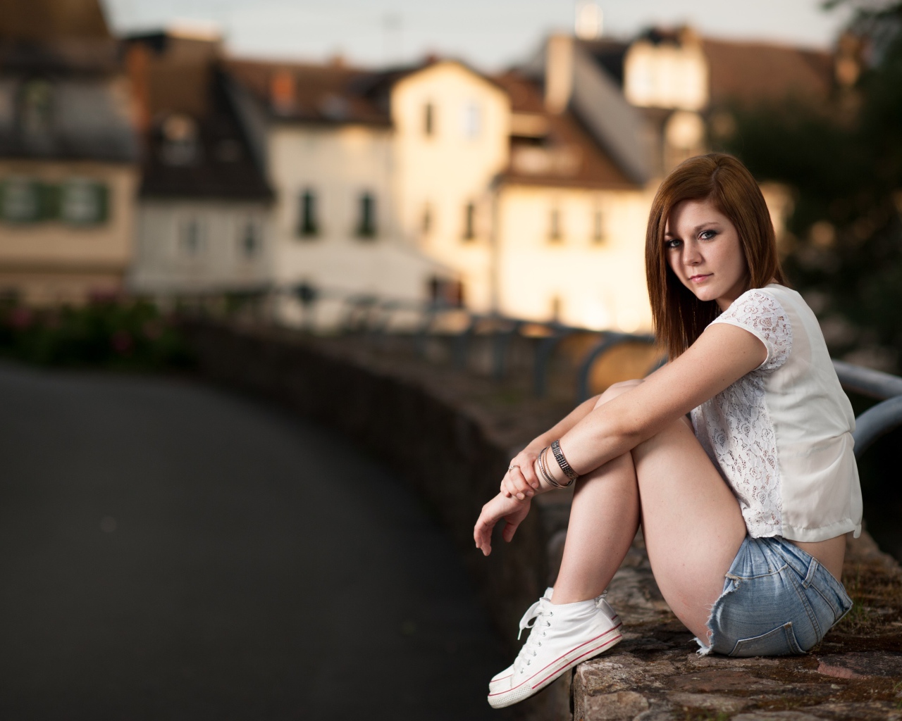 Молодая девушка с короткими  волосами сидит на улице