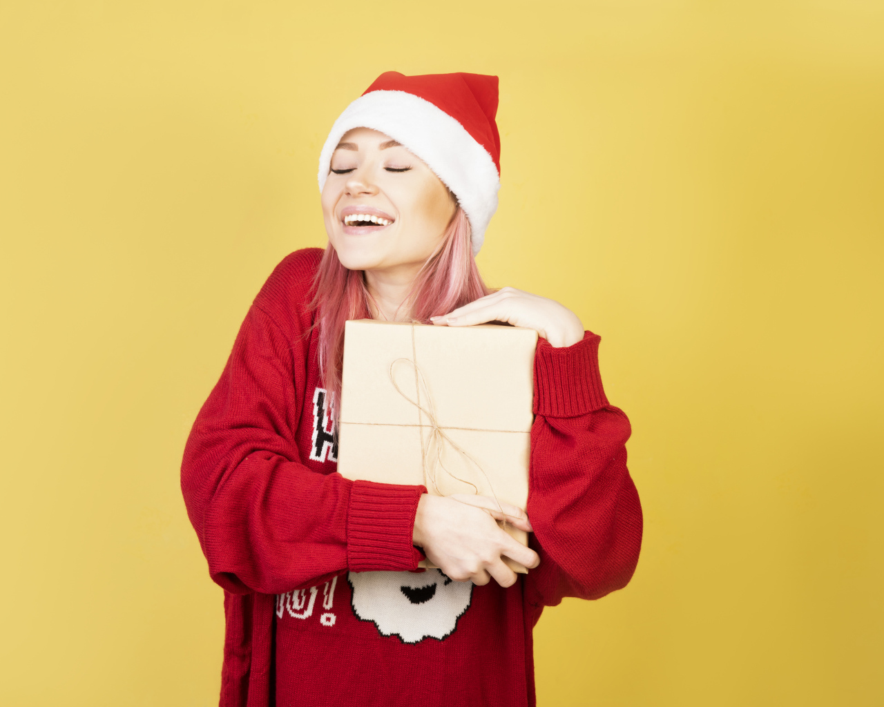 Улыбающаяся девушка в красном свитере с подарком на желтом фоне