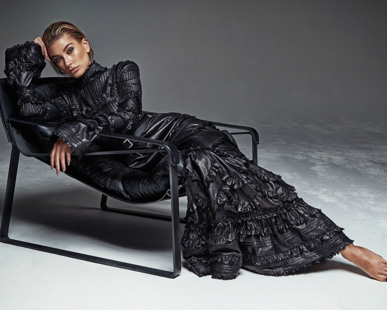 Beautiful model Hayley Baldwin in a long dress lies in an armchair