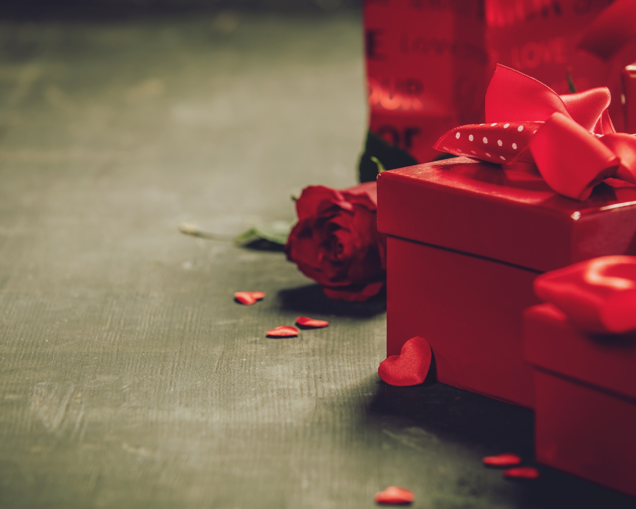 Красные коробки с подарками на столе с розой 