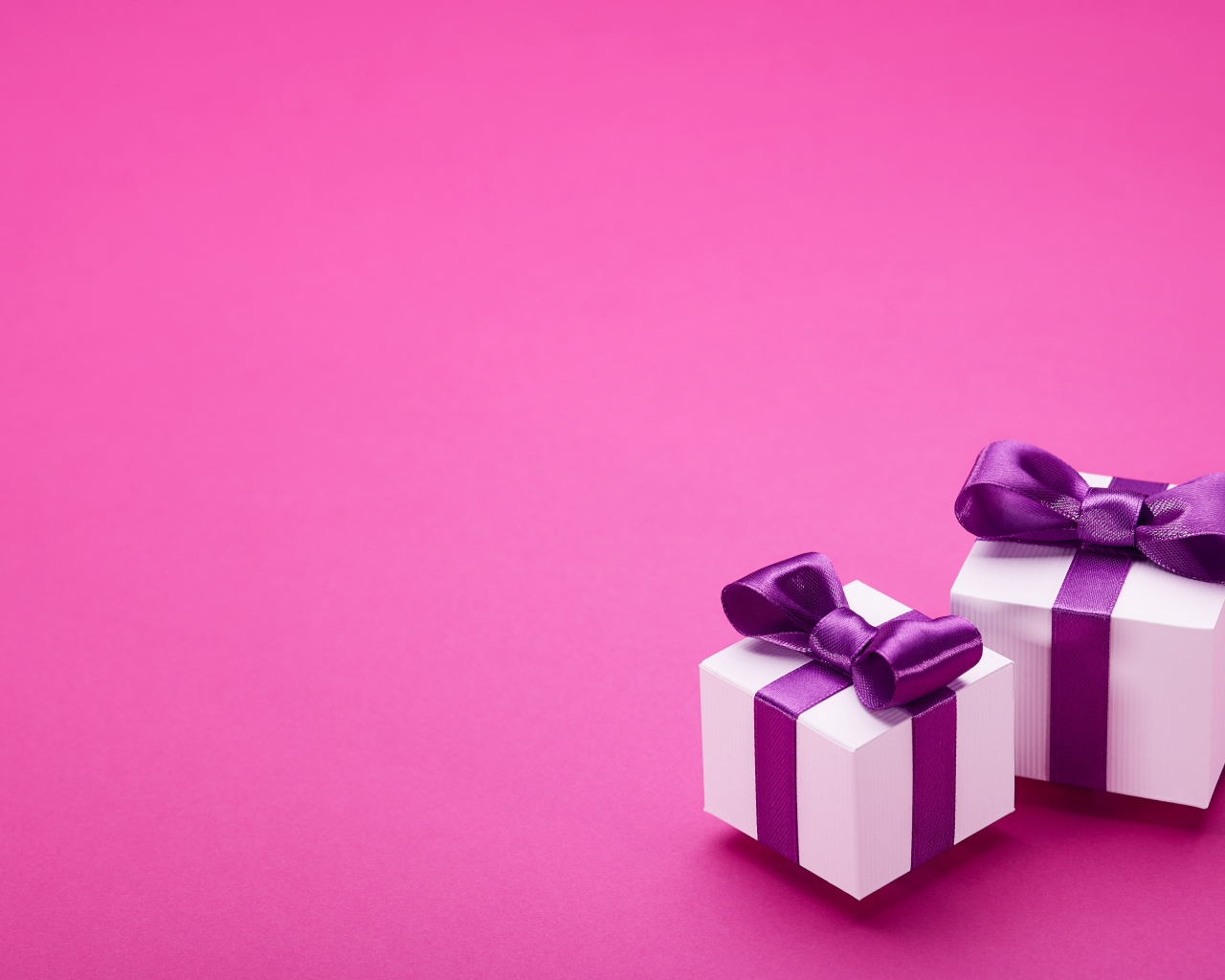 Два подарка с бантами на розовом фоне 
