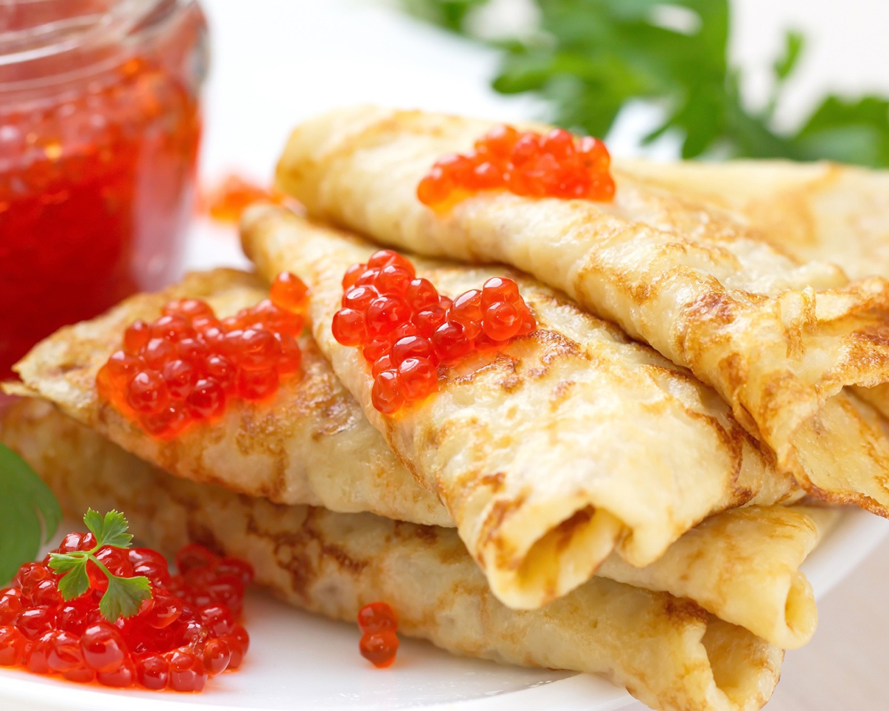 Аппетитные тонкие блины с красной икрой на тарелке с петрушкой угощение на Масленицу