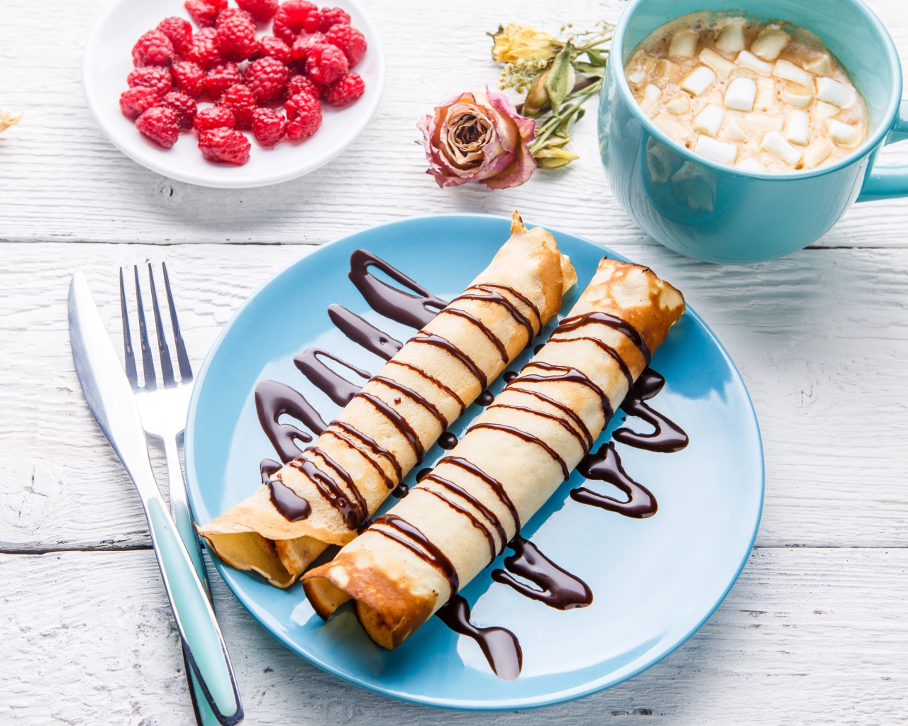 Тонкие блины с шоколадом на столе с ягодами малины и какао 