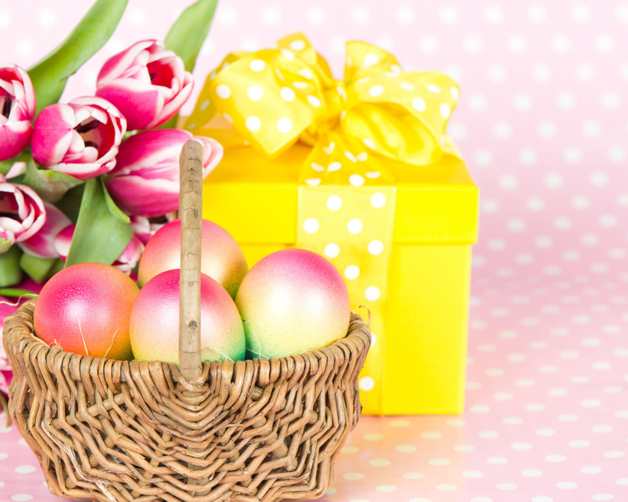 Корзина с пасхальными яйцами на столе с подарком и букетом тюльпанов 