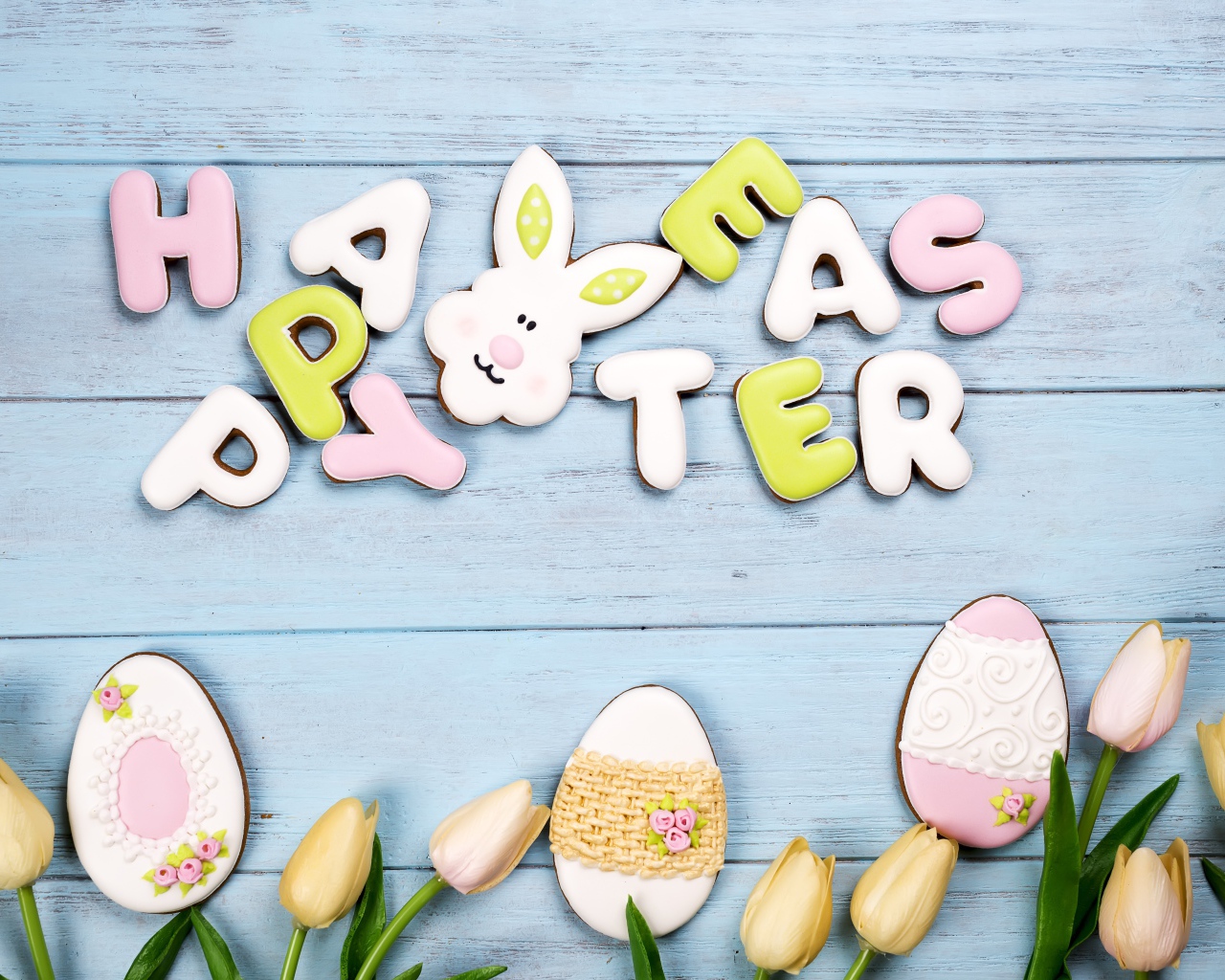 Красивое пасхальное печенье на столе с тюльпанами 