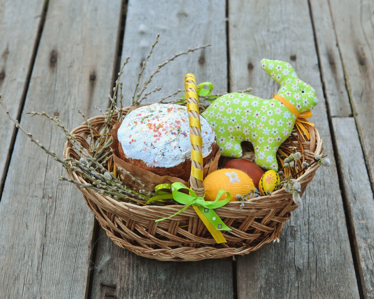 Пасхальный кулич в корзинке с игрушками  на столе 