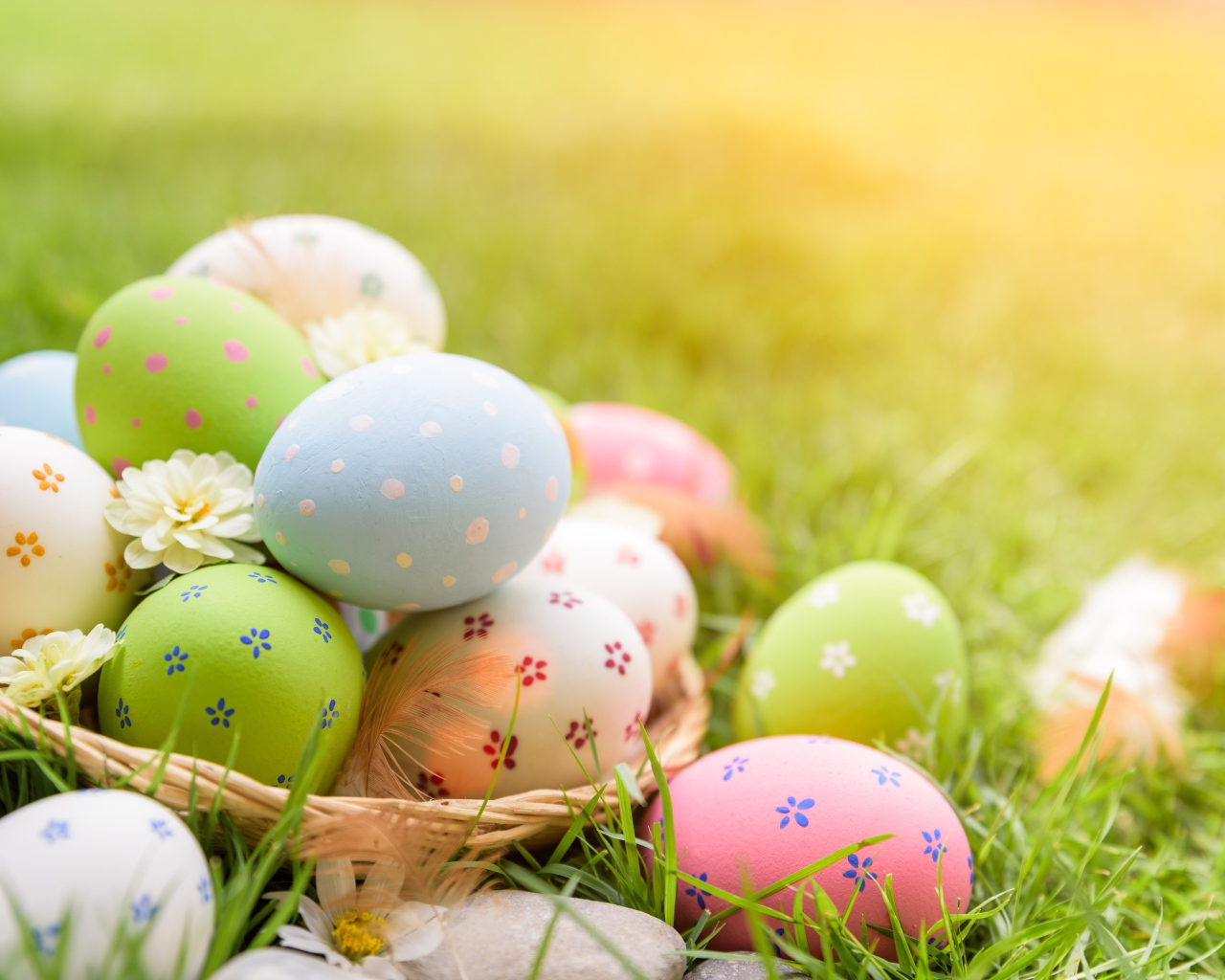 Разноцветные пасхальные яйца в корзинке на зеленой траве