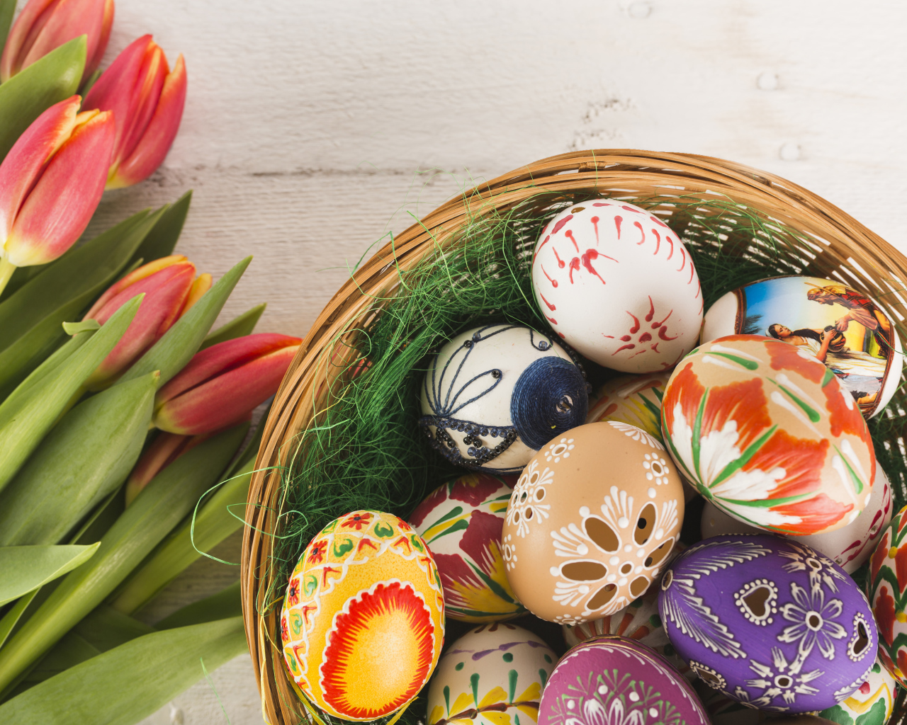 Multi-colored colored eggs in a basket with a bouquet of tulips for Easter