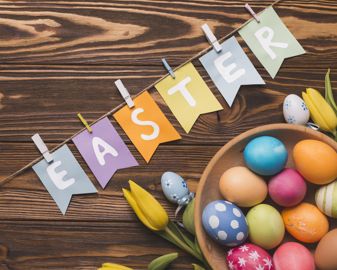 Надпись Пасха на столе с крашеными яйцами и тюльпанами