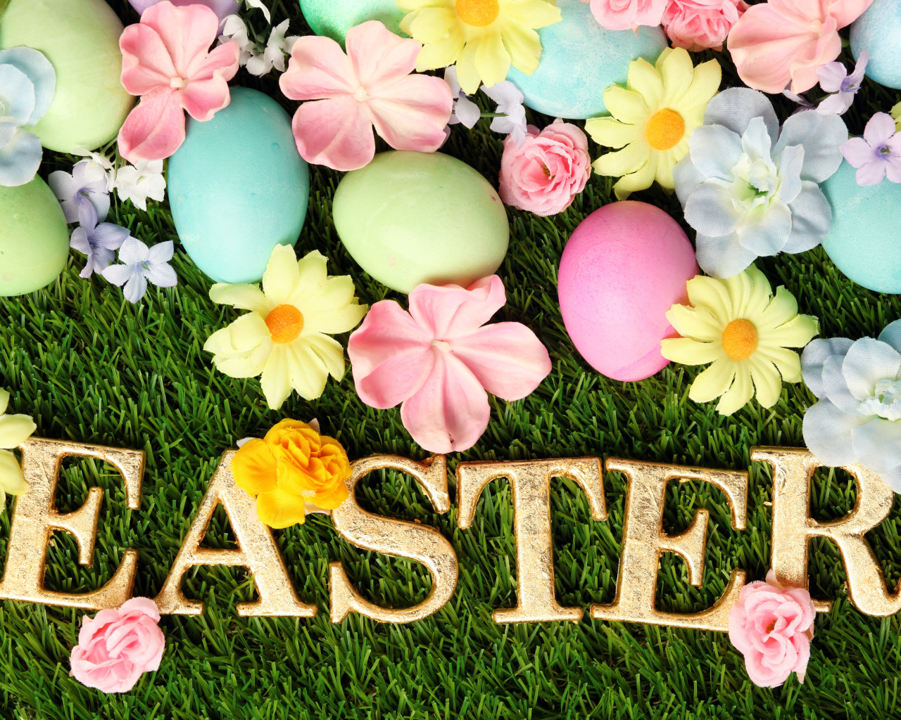 Надпись на траве с разноцветными яйцами и цветами на Пасху