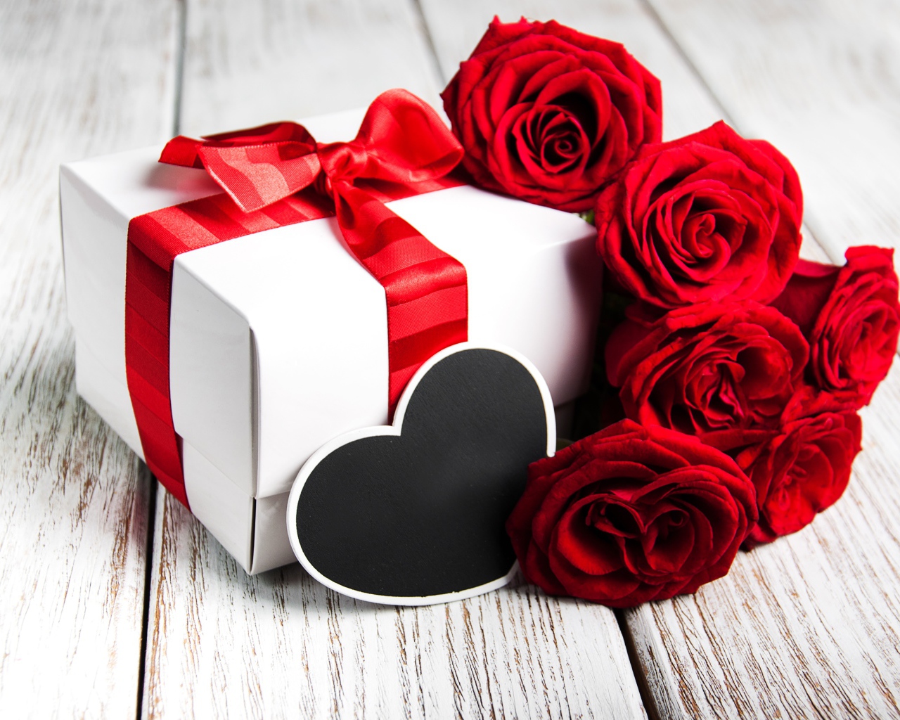 Букет красивых красных роз на столе с подарком для любимой на 8 марта