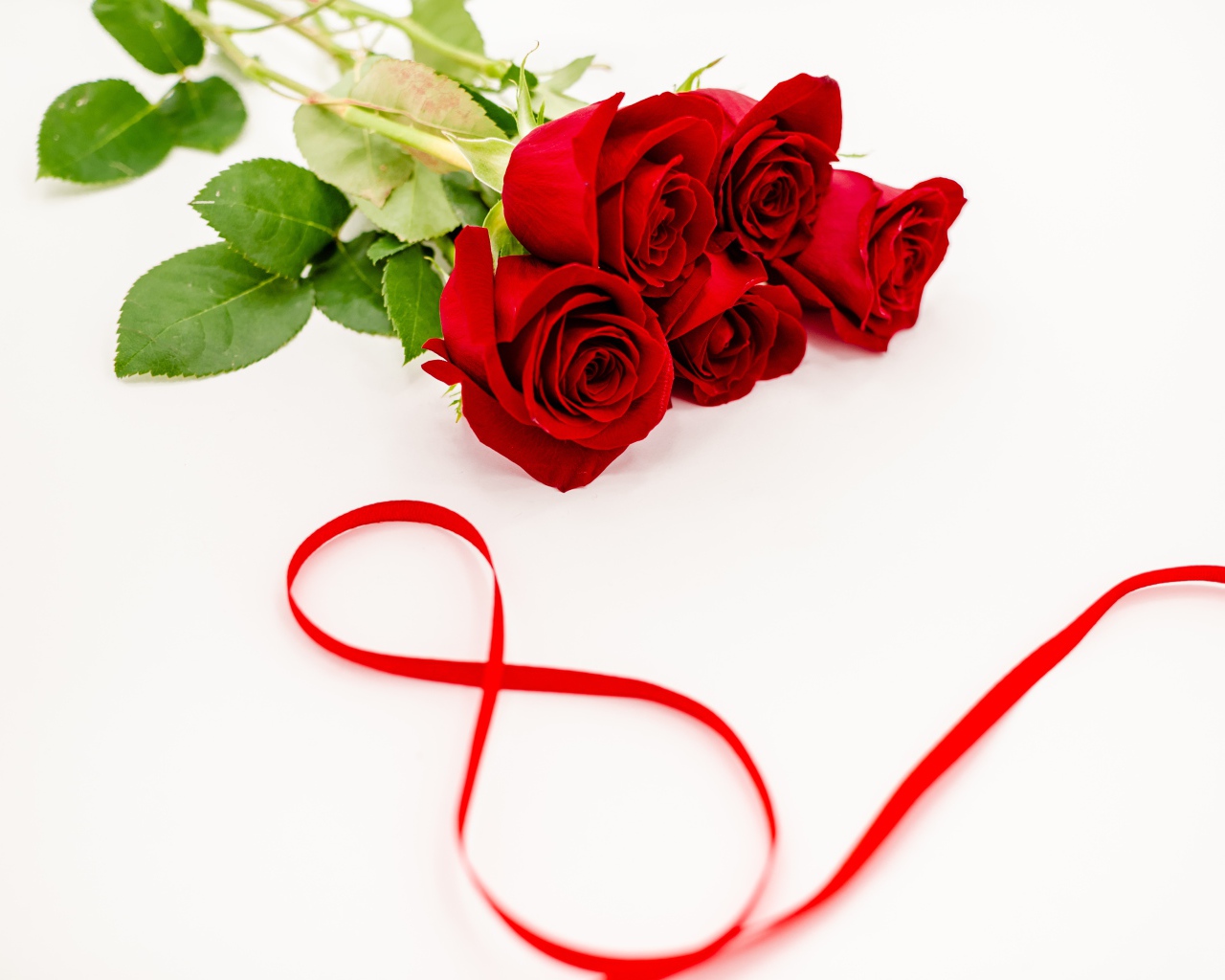 Букет красных роз и цифра 8 из атласной ленты на белом фоне