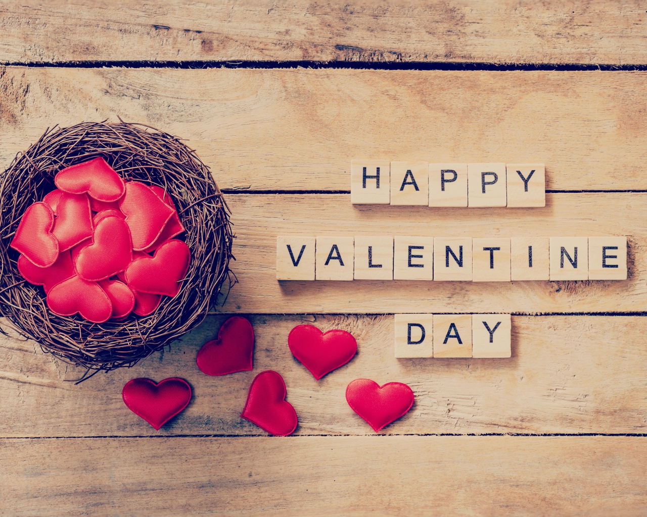 Кубики и гнездо с сердечками на деревянном столе на День Святого Валентина