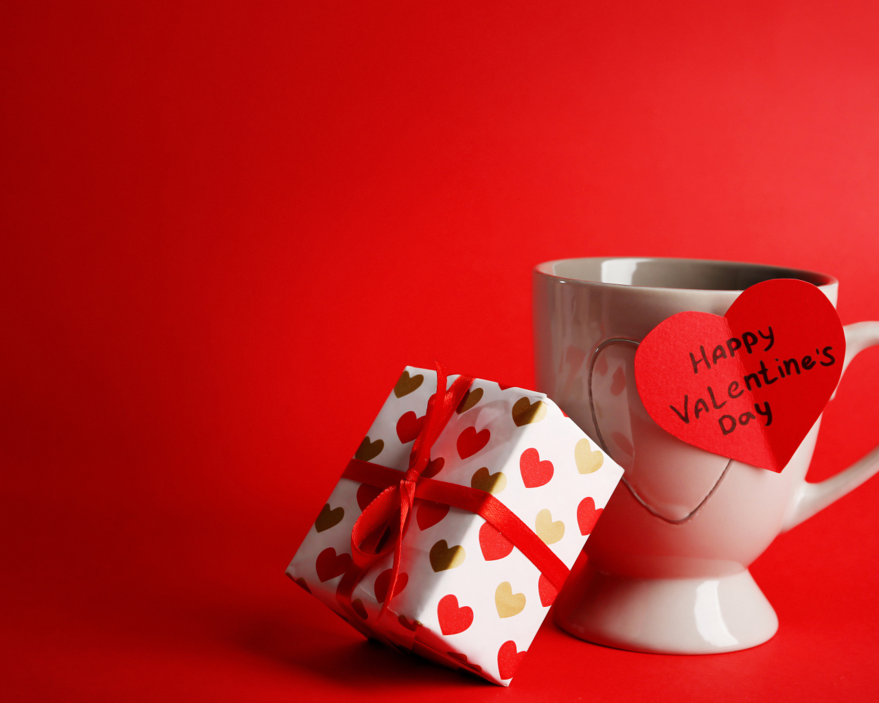 Кружка, сердечко и подарок на красном фоне на День Святого Валентина 