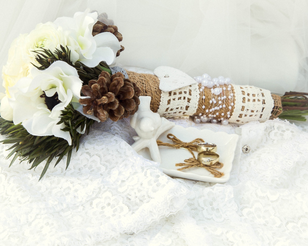 Букет невесты из цветом анемоны лежит на платье с обручальными кольцами