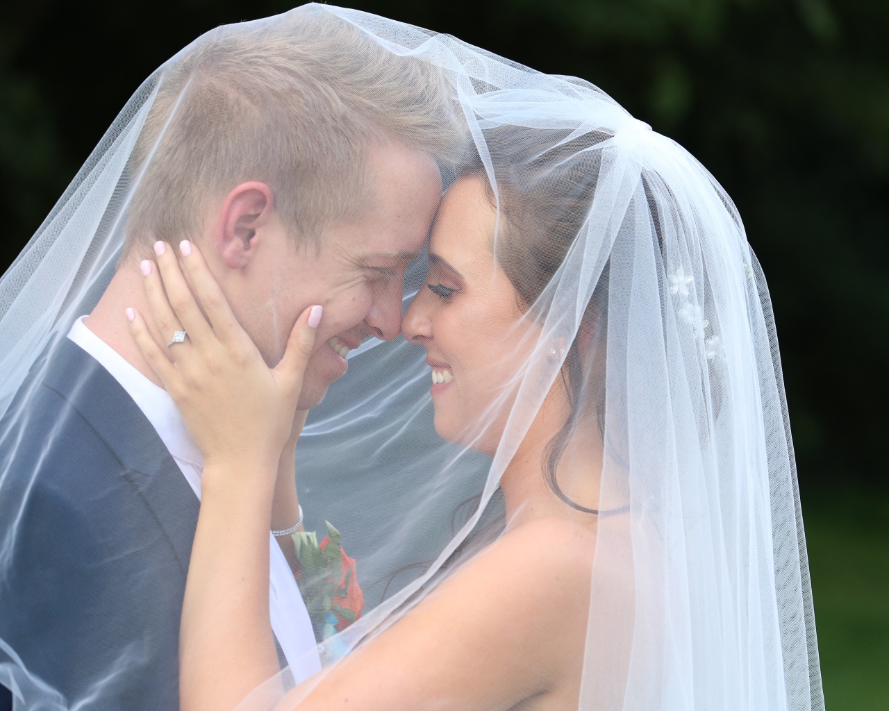 Жених и невеста стоят под белой фатой