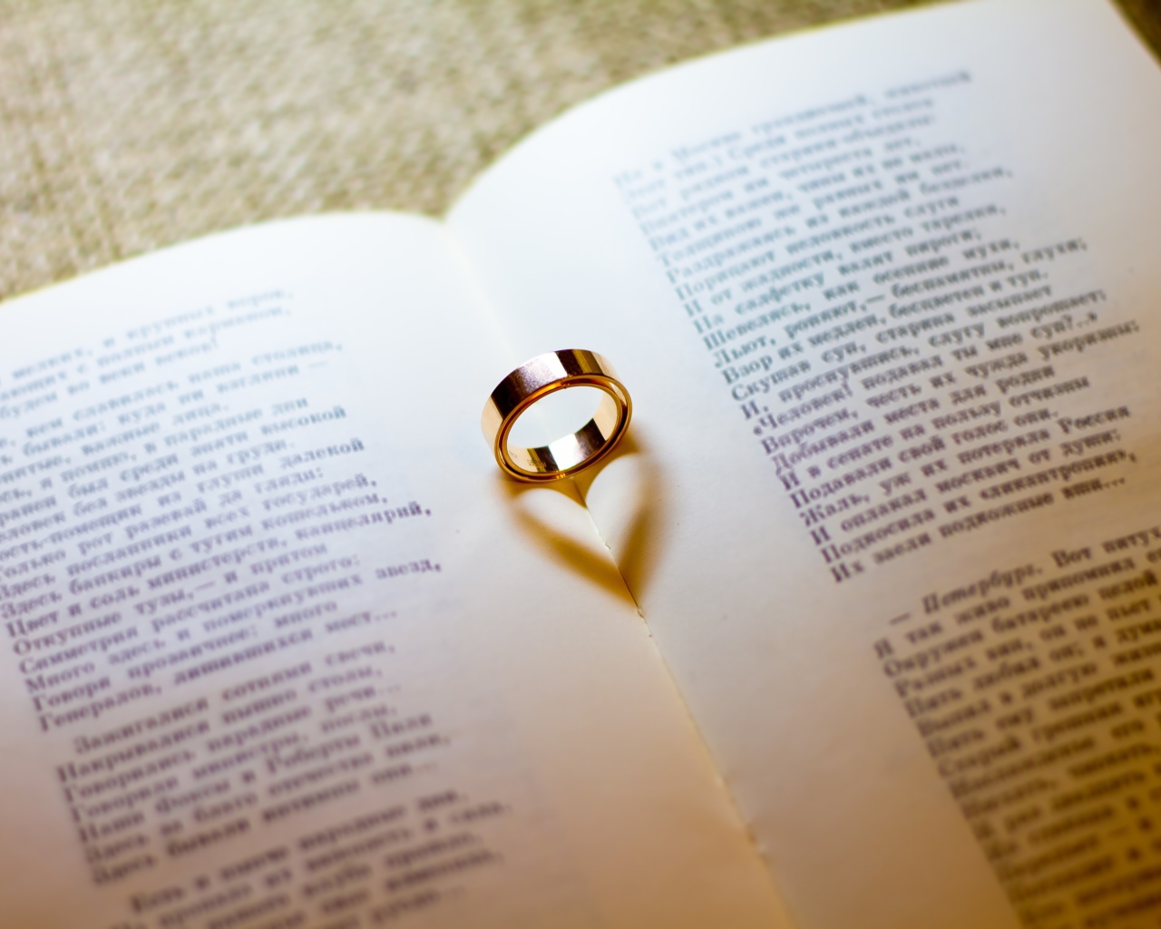 Золотое обручальное кольцо лежит на открытой книге