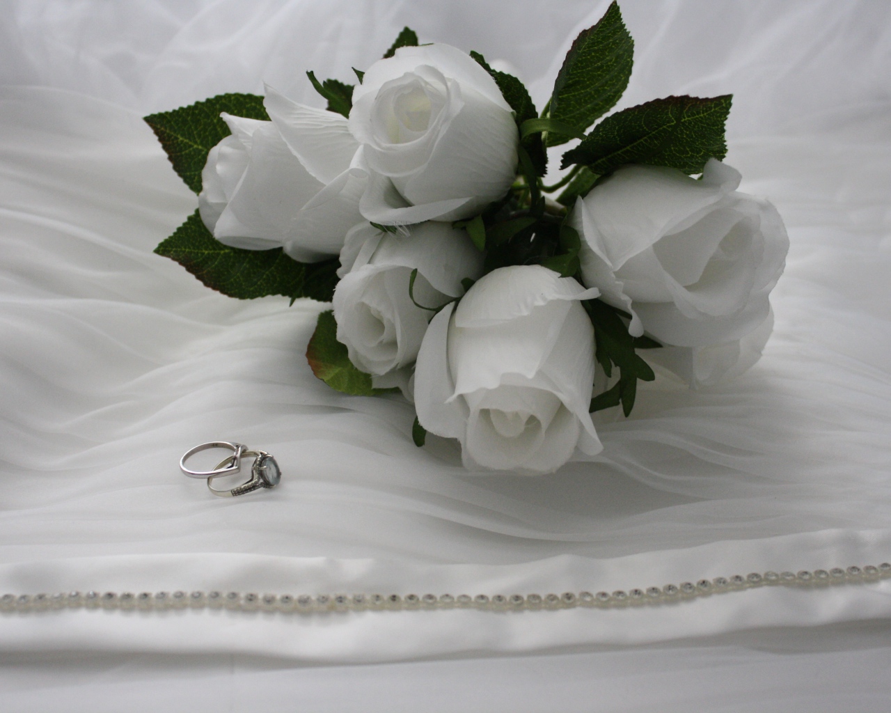 Белые бутоньерки с кольцами на белом покрывале 