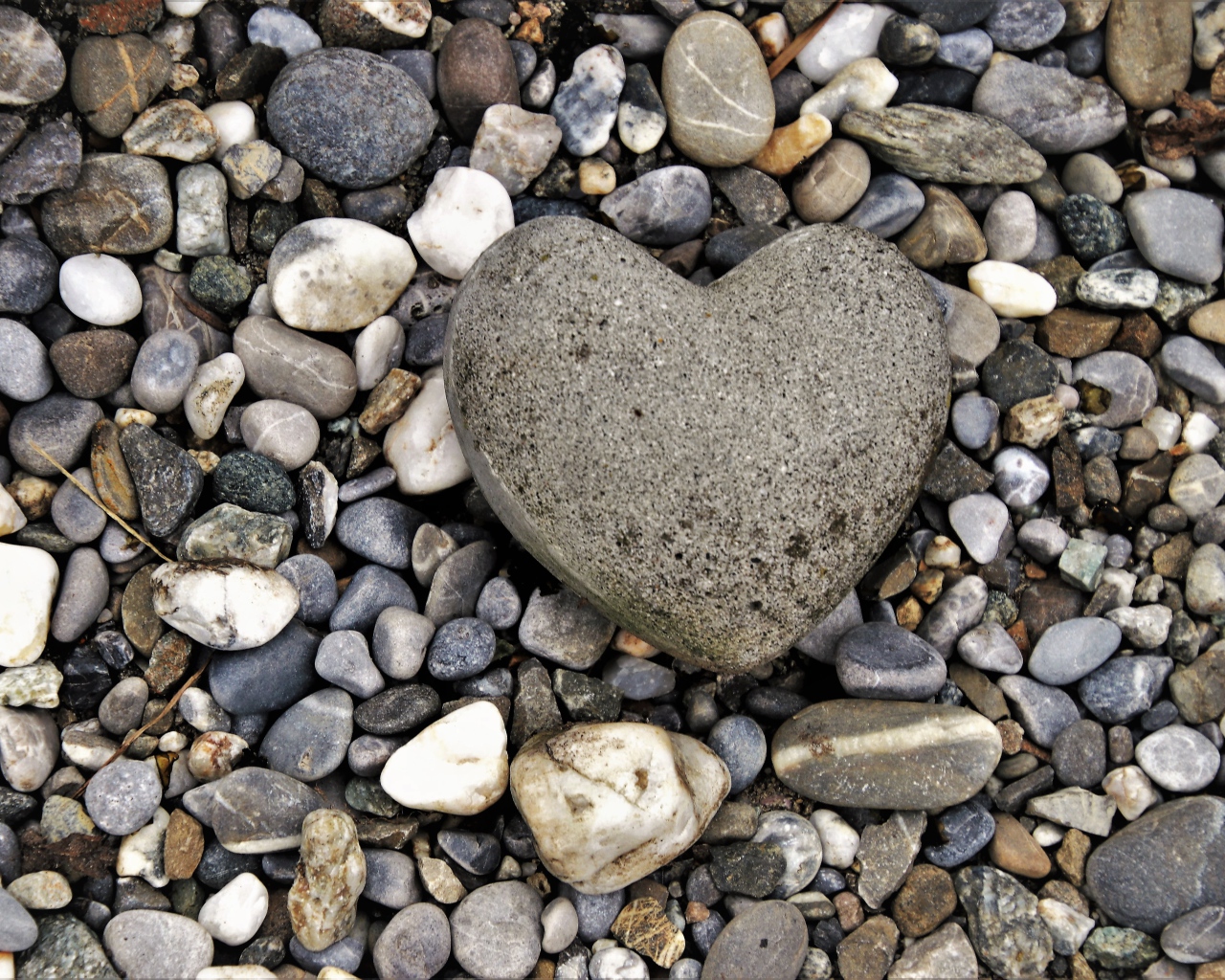 Большой камень в форме сердца лежит на морской гальке