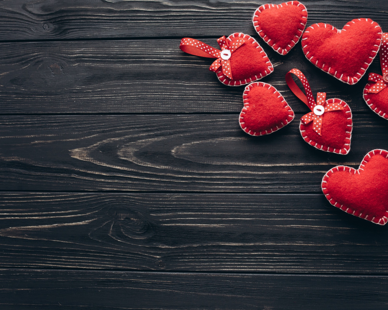 Много красных сердечек из фетра на деревянном столе