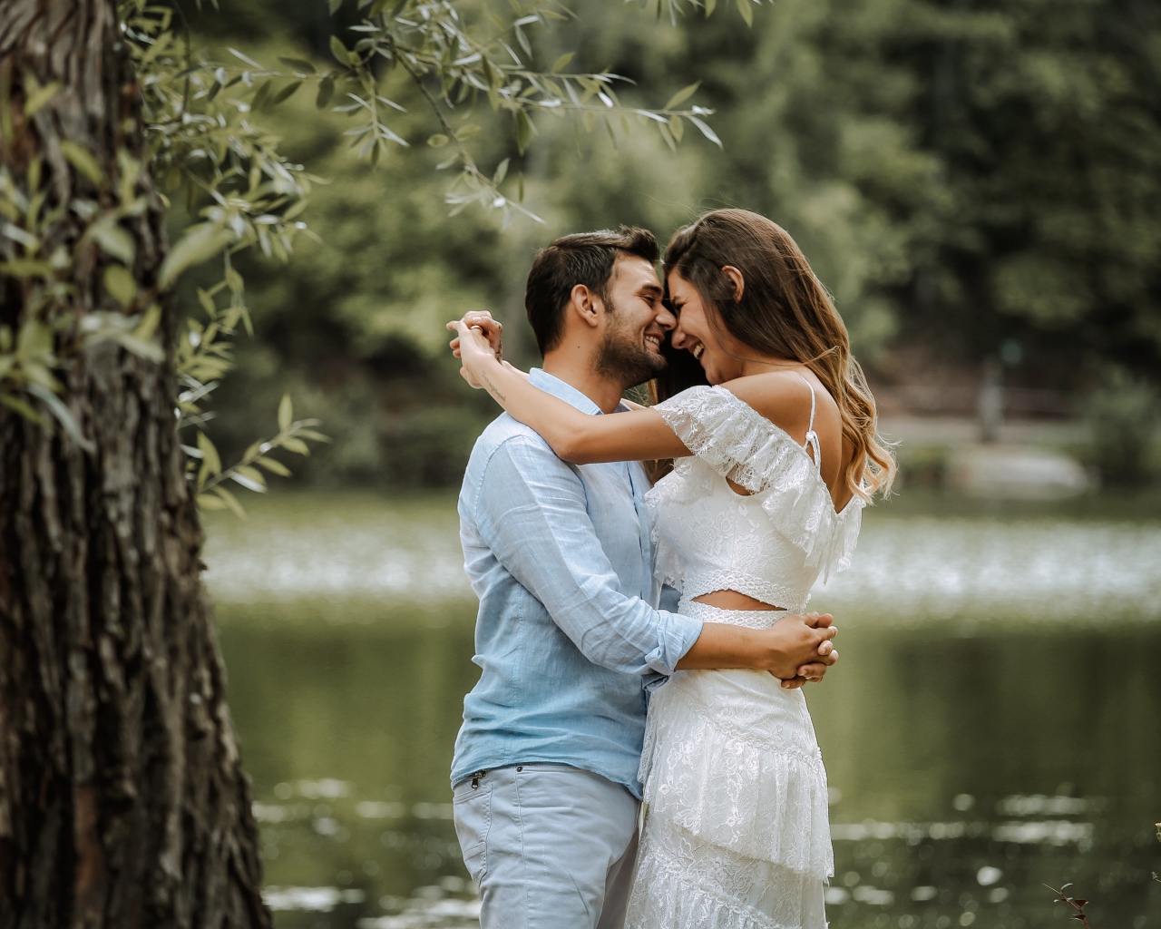 Влюбленная пара стоит у пруда в парке 