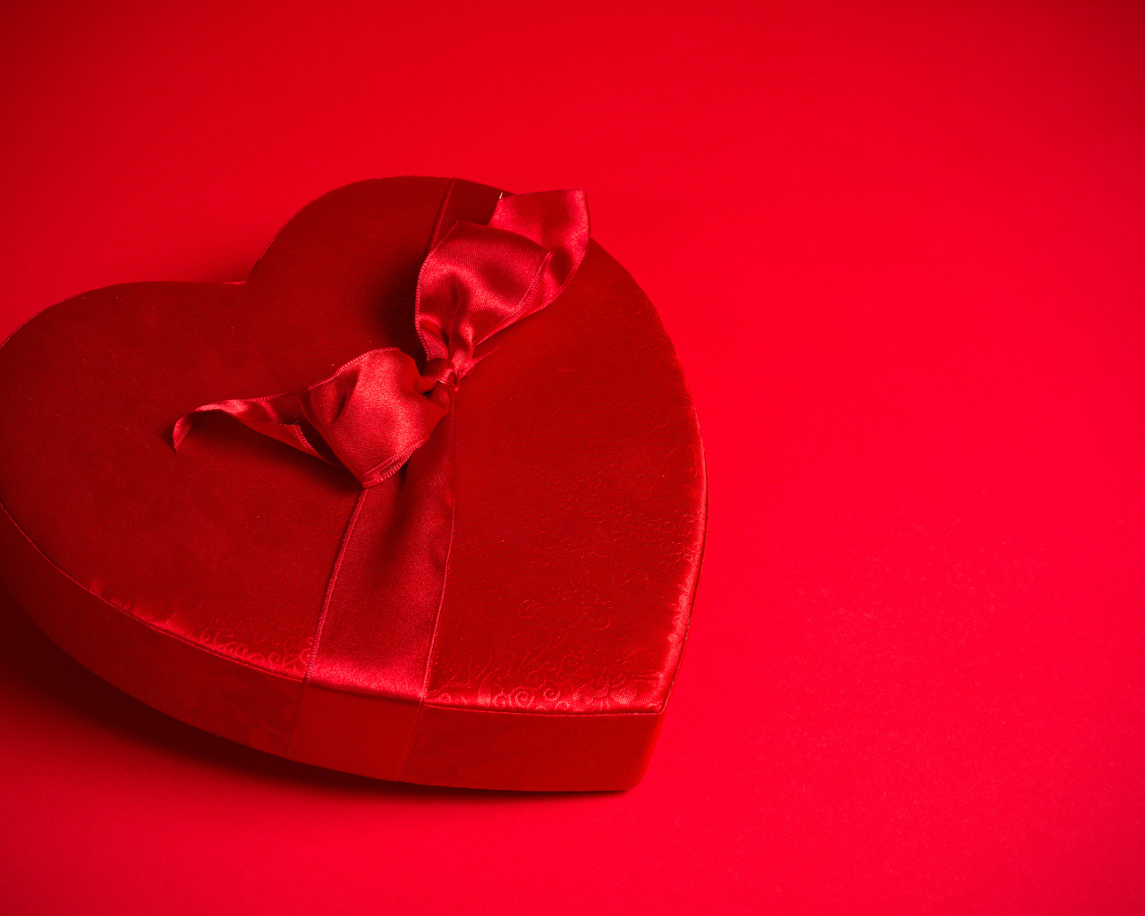 Большое красное сердце с бантом на красном фоне