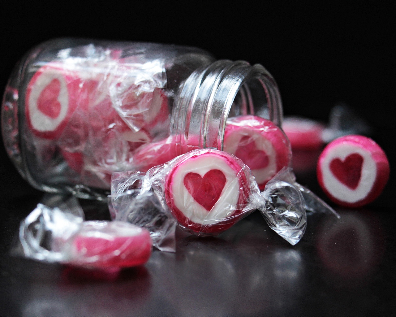 Конфеты с сердцем в стеклянной банке на черном фоне