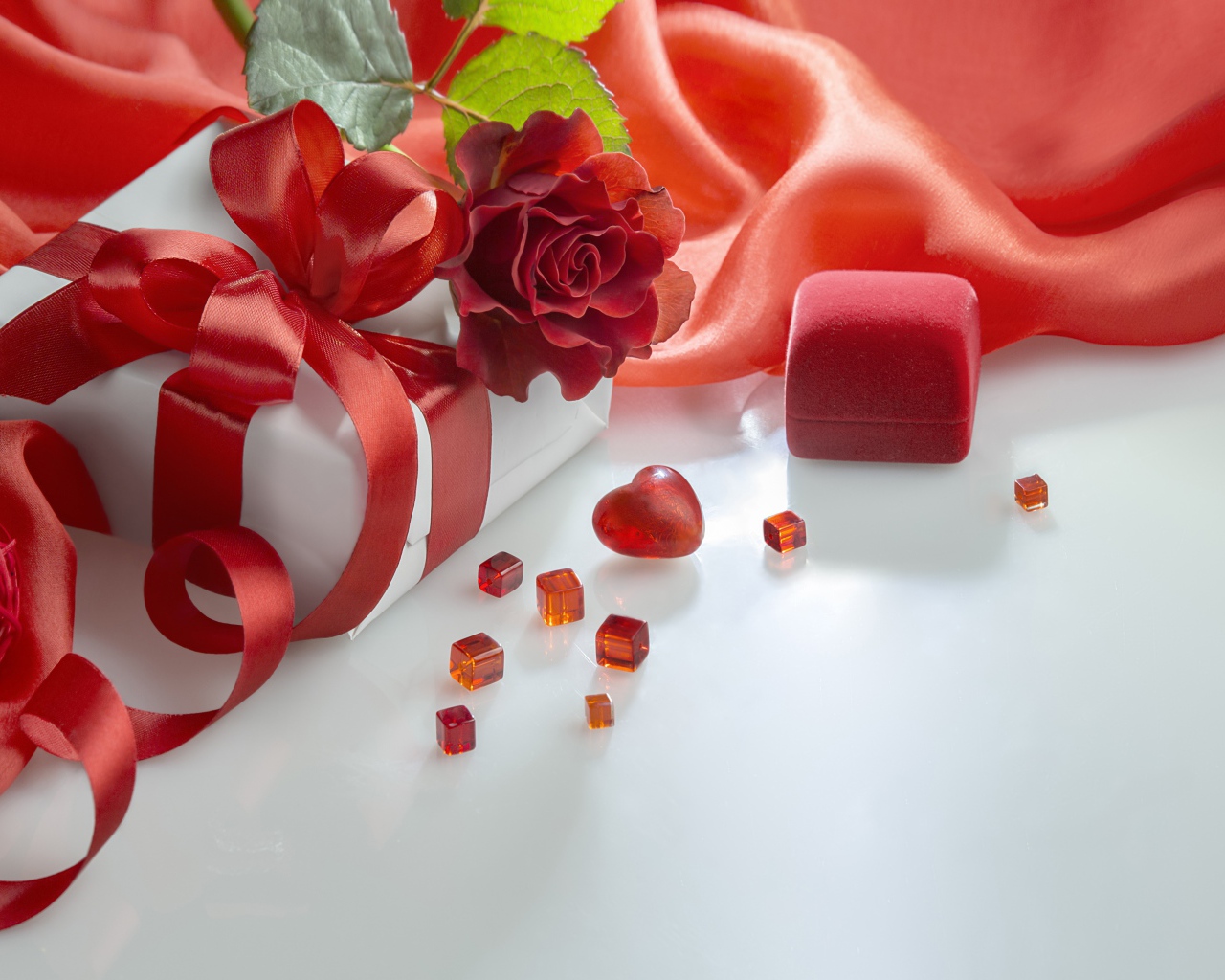 Подарки на белом столе с розой и красной тканью