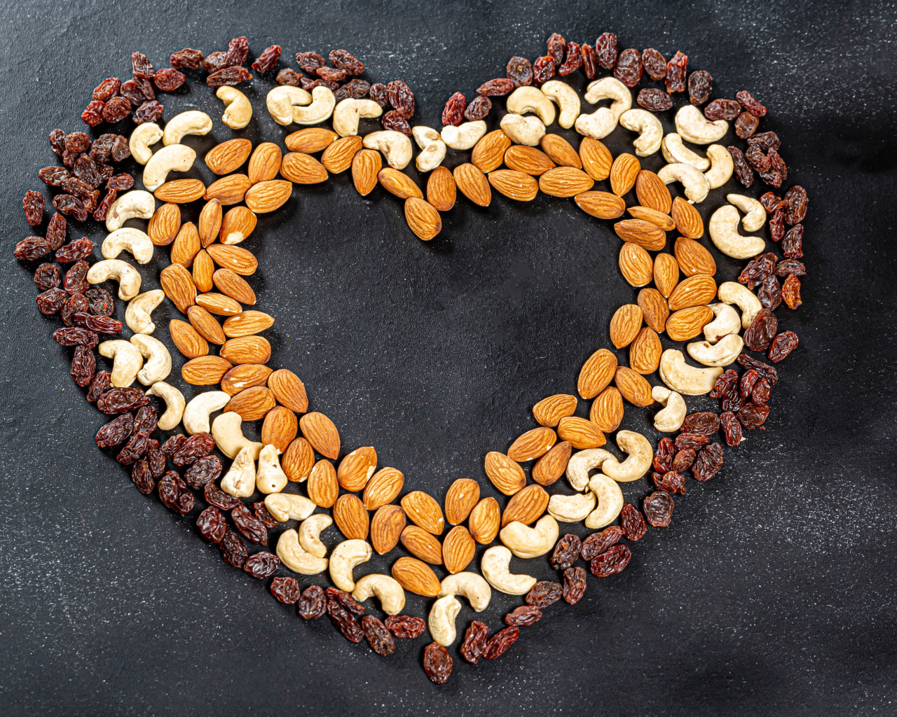 Сердце из орехов и изюма на сером фоне