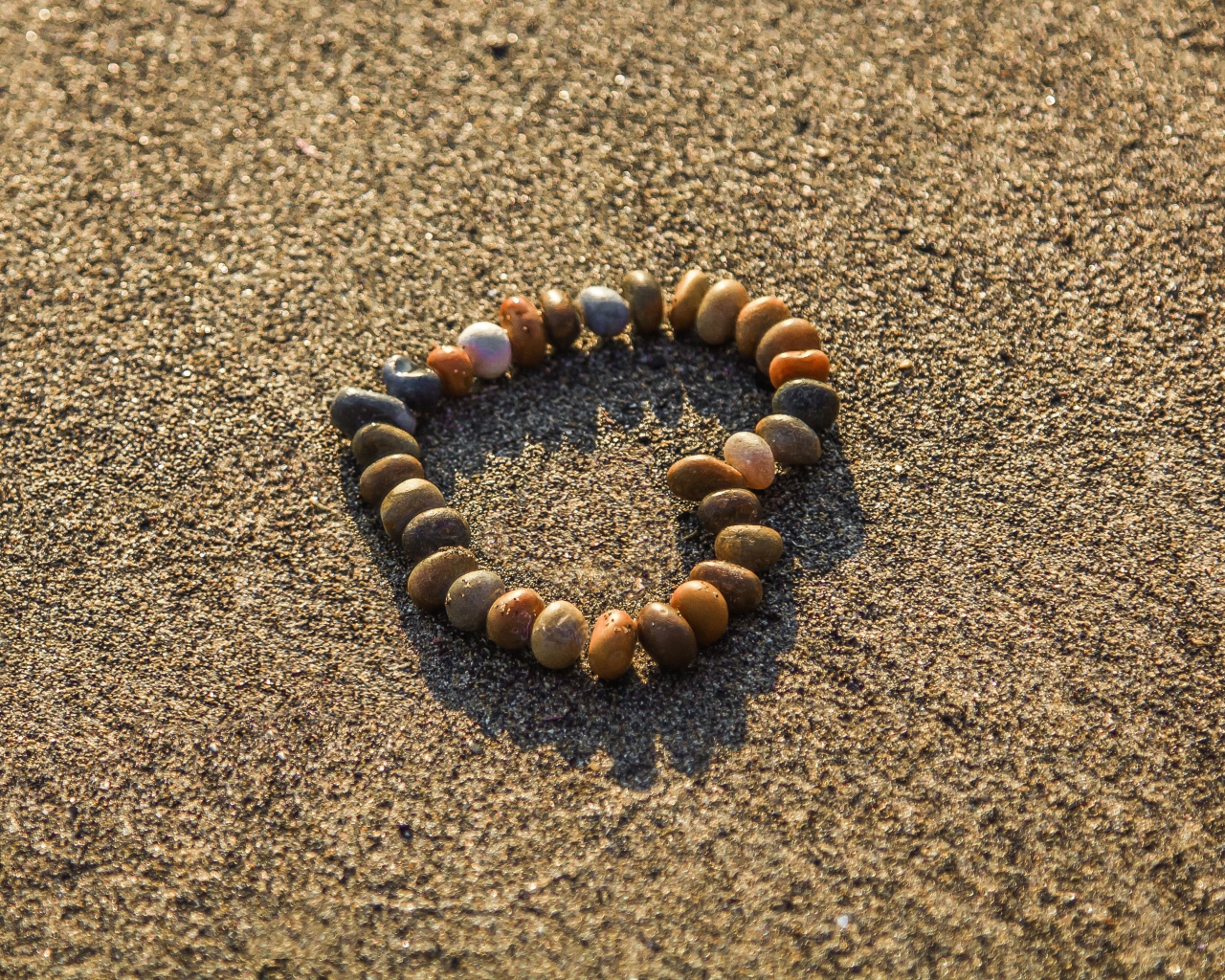 Сердце из мелкий морских камей на песке 