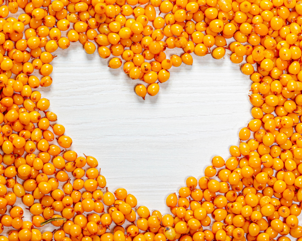 Сердце из ягод облепихи на столе 