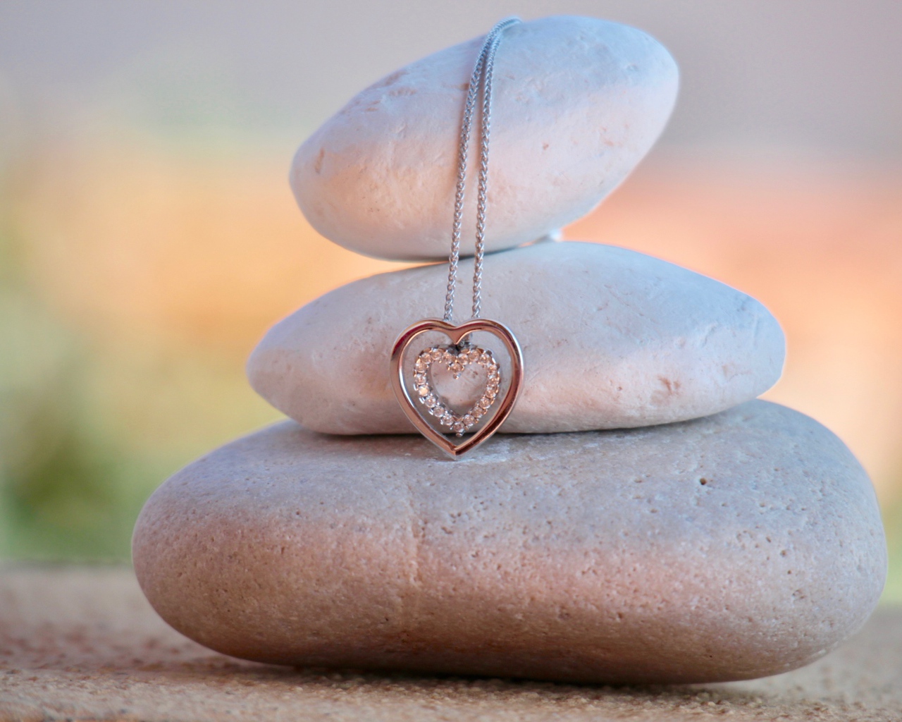 Золотой кулон в форме сердца висит на камнях 