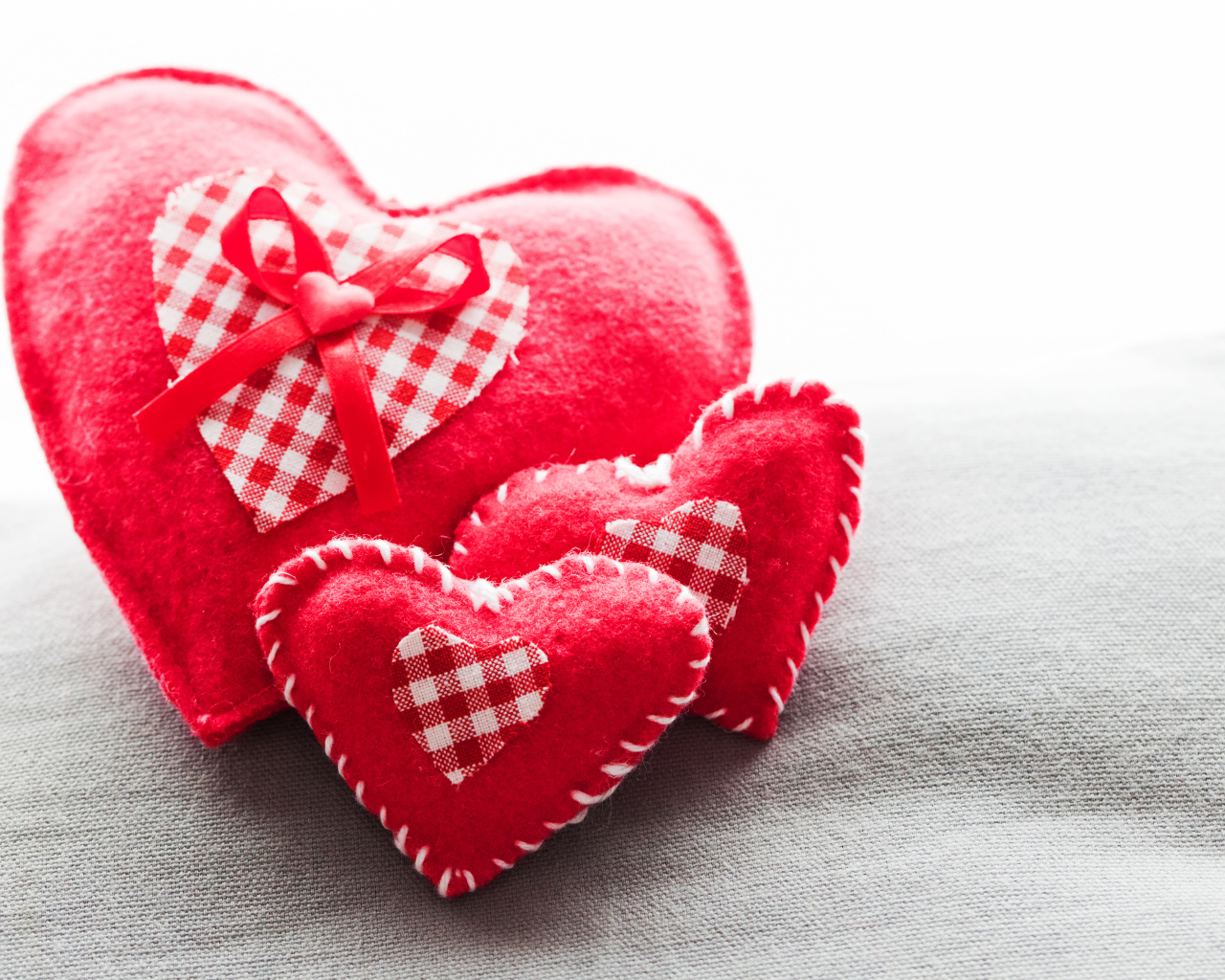 Сердечки из ткани лежат на серой поверхности 