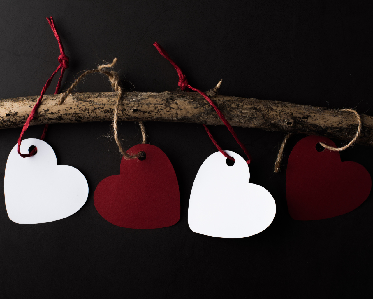 Бумажные сердечки на ветке на черном фоне