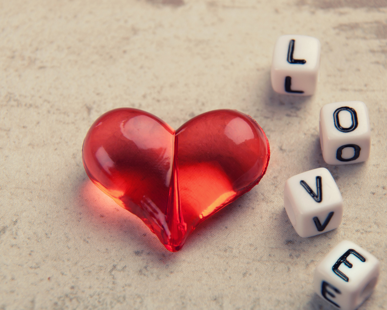 Красное стеклянное сердце на столе с кубиками