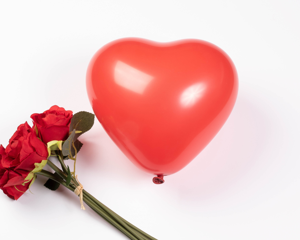 Красный шарик в форме сердца с букетом роз на белом фоне