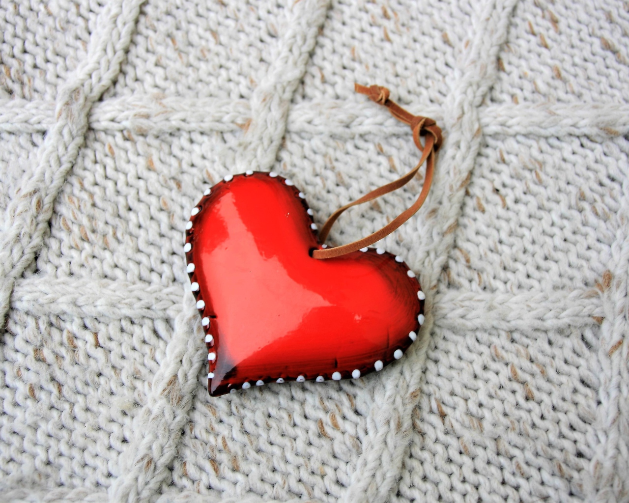 Красное сердце лежит на вязаном свитере 