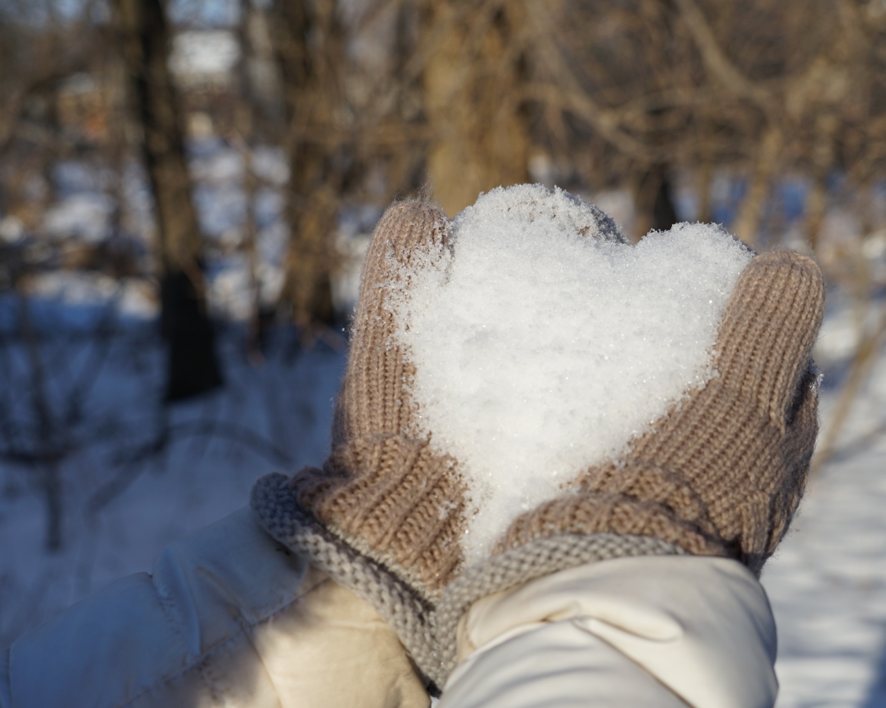 Снег в руках у девушки в перчатках 