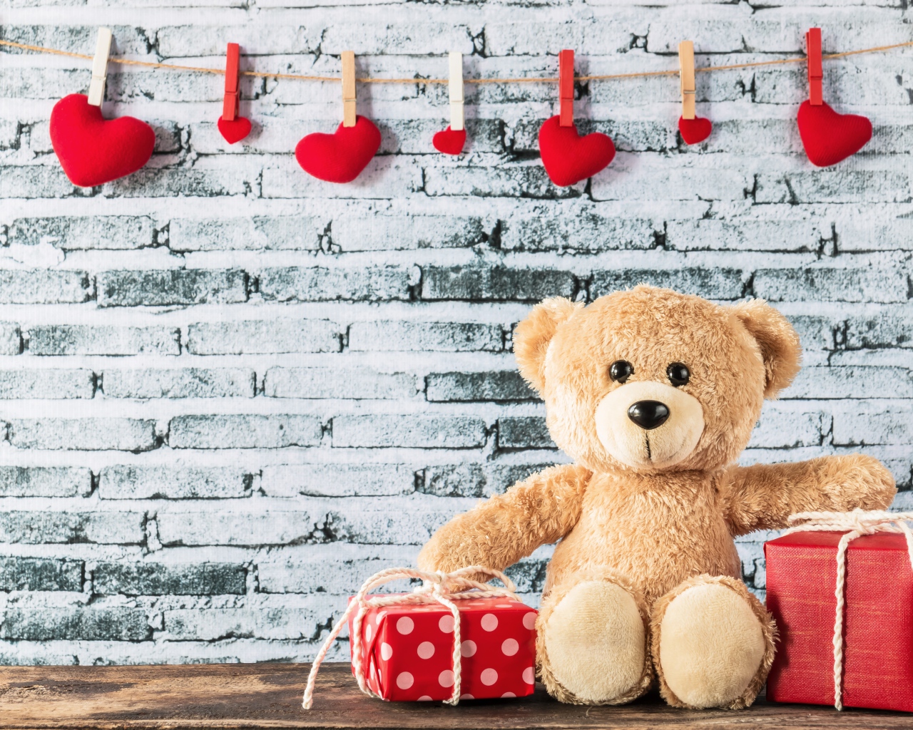 Медвежонок Тедди с подарками на фоне стены с сердечками