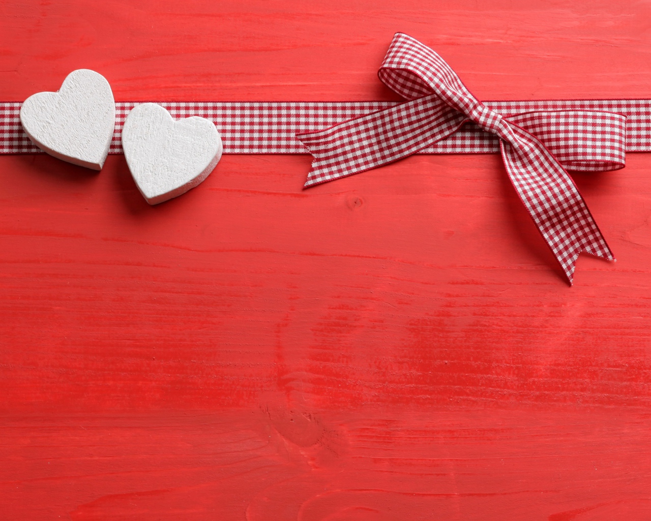 Два сердечка с бантом на красном фоне