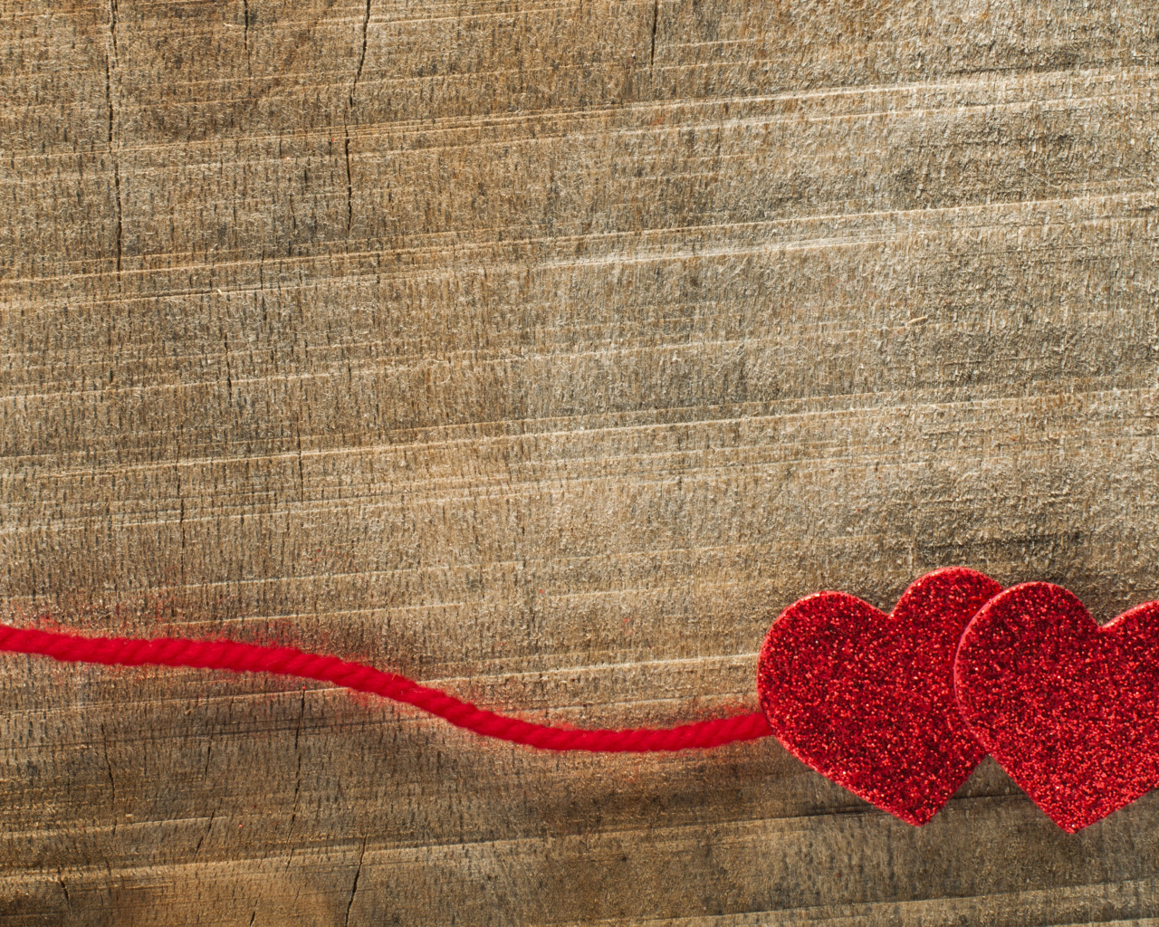 Два красных сердца со шнурком на деревянном фоне