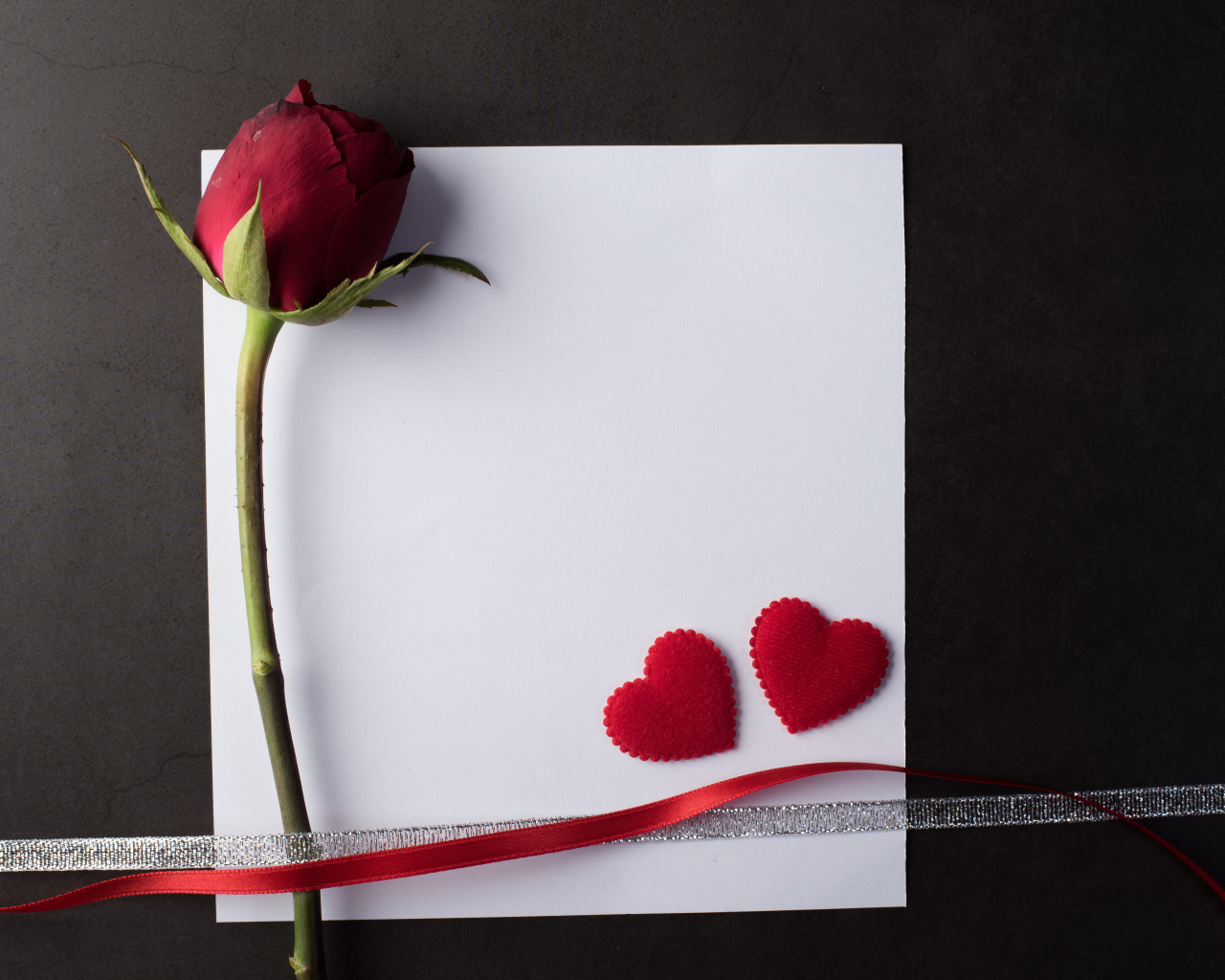 Белый лист бумаги, роза и ленточки на сером фоне