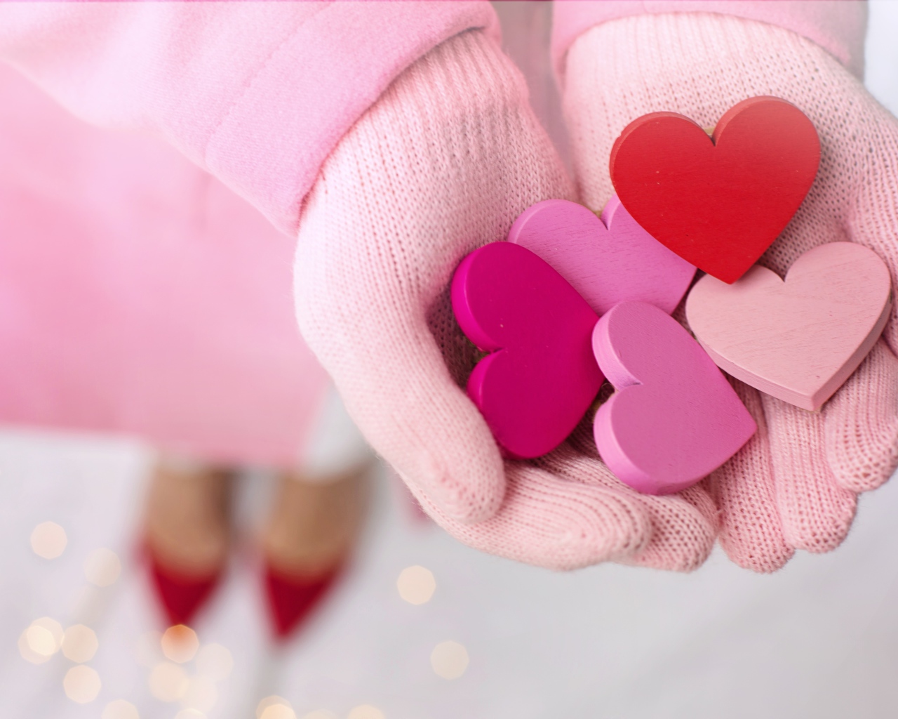 Деревянные сердечки в руках девушки в розовых перчатках 