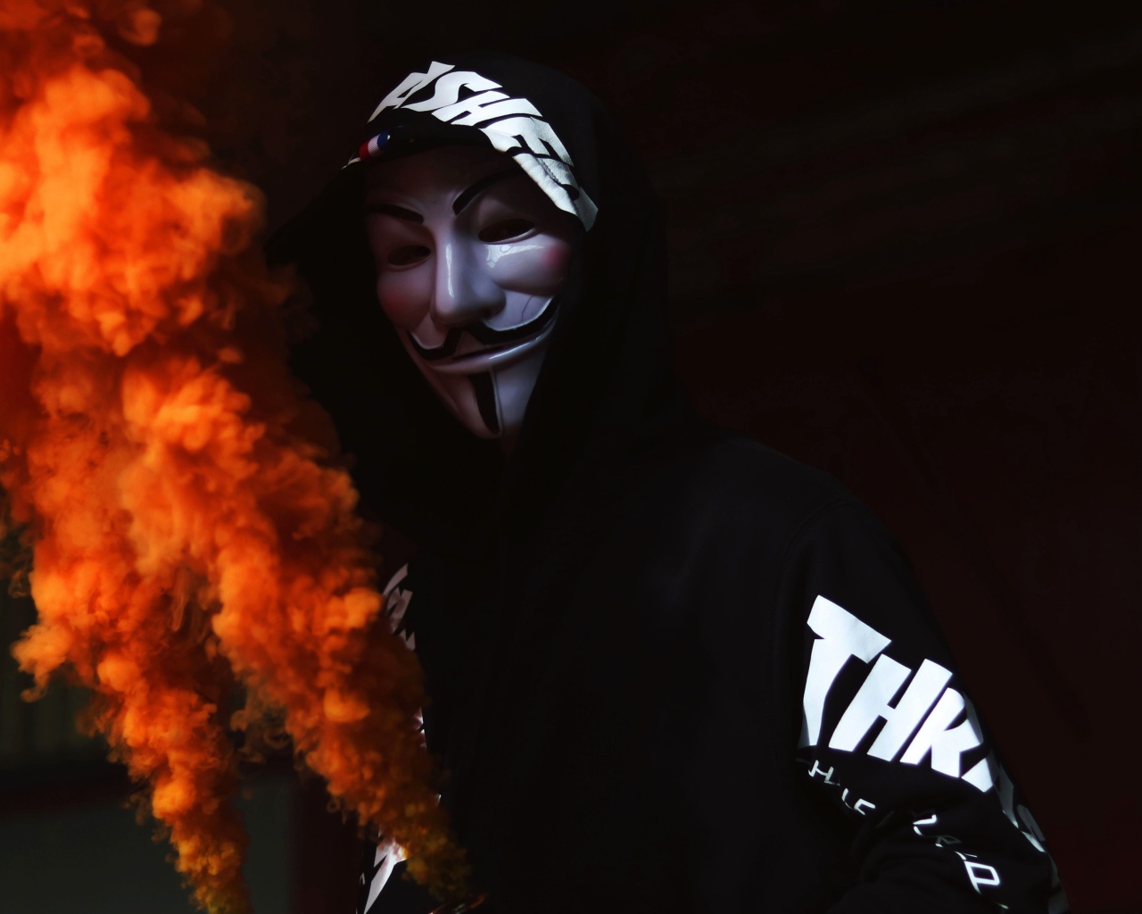 A man in an anonymous mask with a smoke bomb in his hand