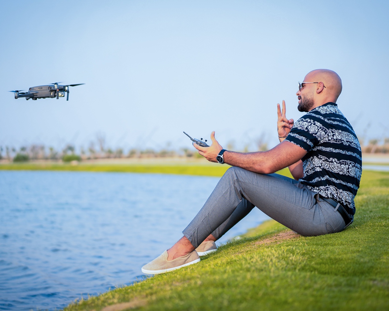 Мужчина запускает квадрокоптер над озером 