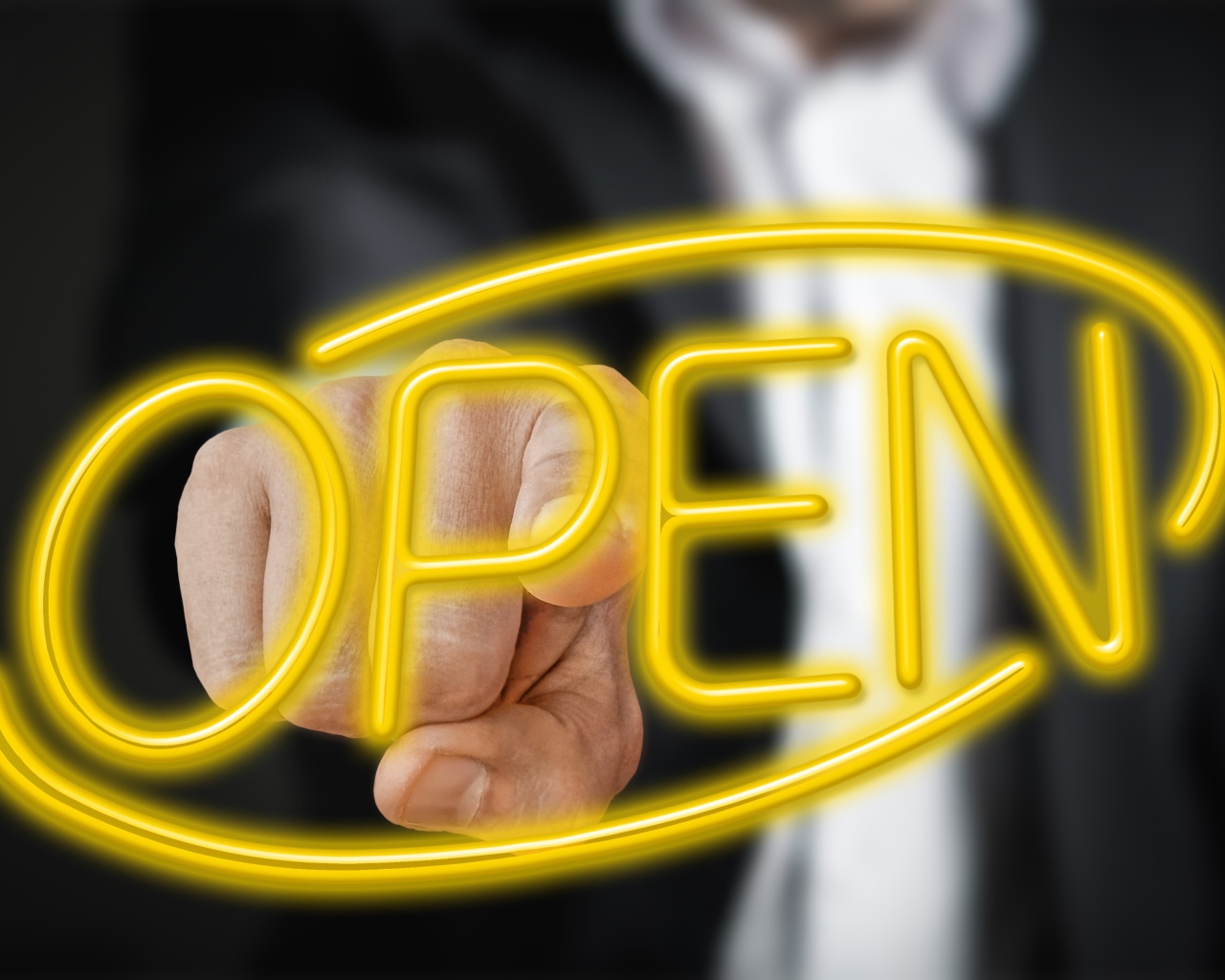 Мужчина трогает пальцем желтую  неоновую  надпись Open 