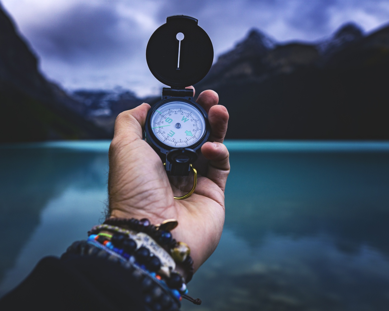 Компас в руке у мужчины на фоне гор 